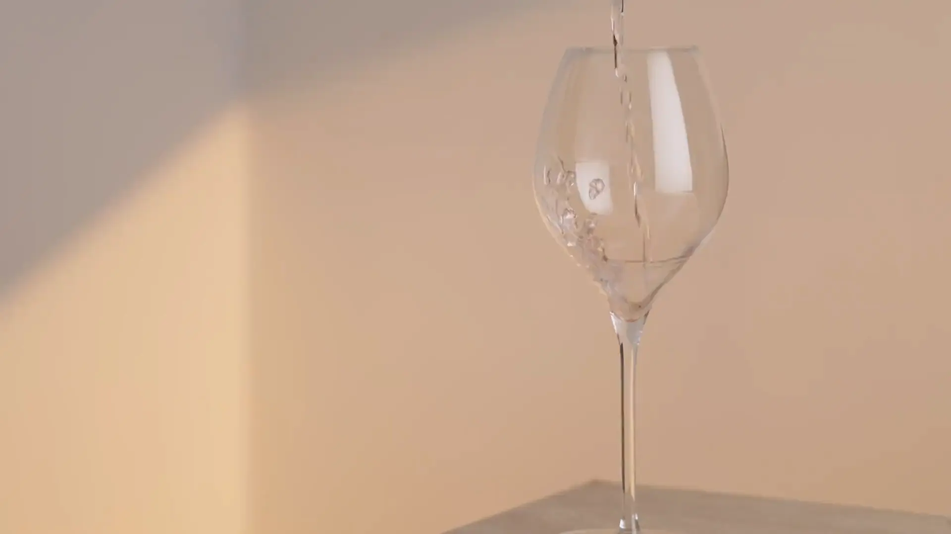 Una copa sirviéndose de Altea Rosé junto a la botella, sobre una mesa a la luz de la tarde